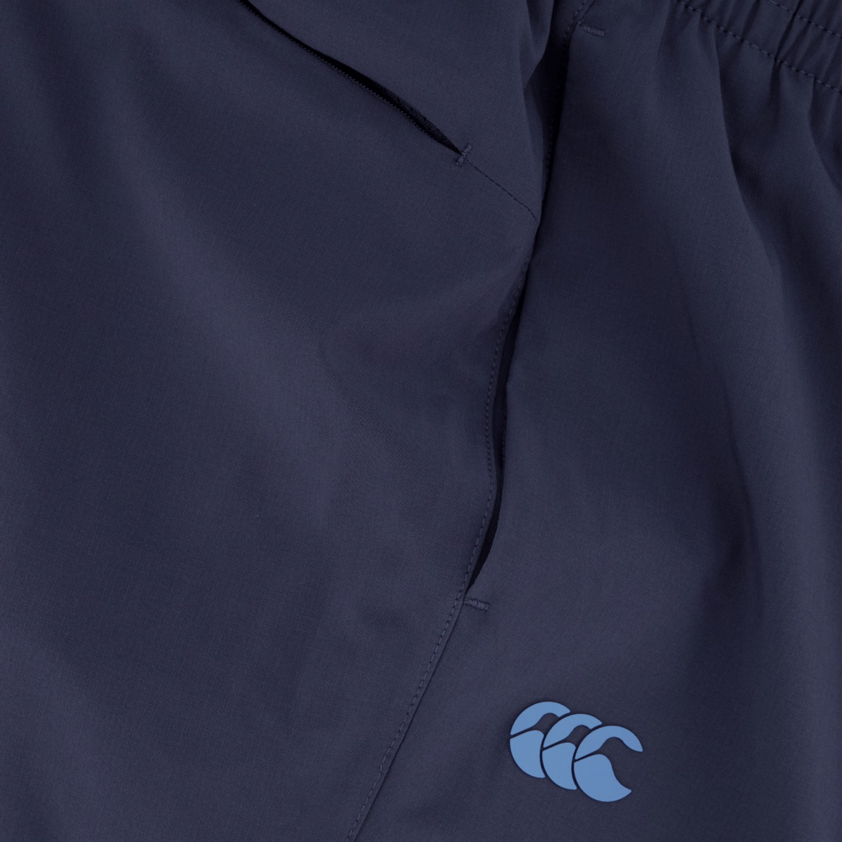 Close-up of Canterbury Tempo+ Training Trackpant in navy, showcasing a tapered fit with an elastic waistband and a blue Canterbury logo on the leg.