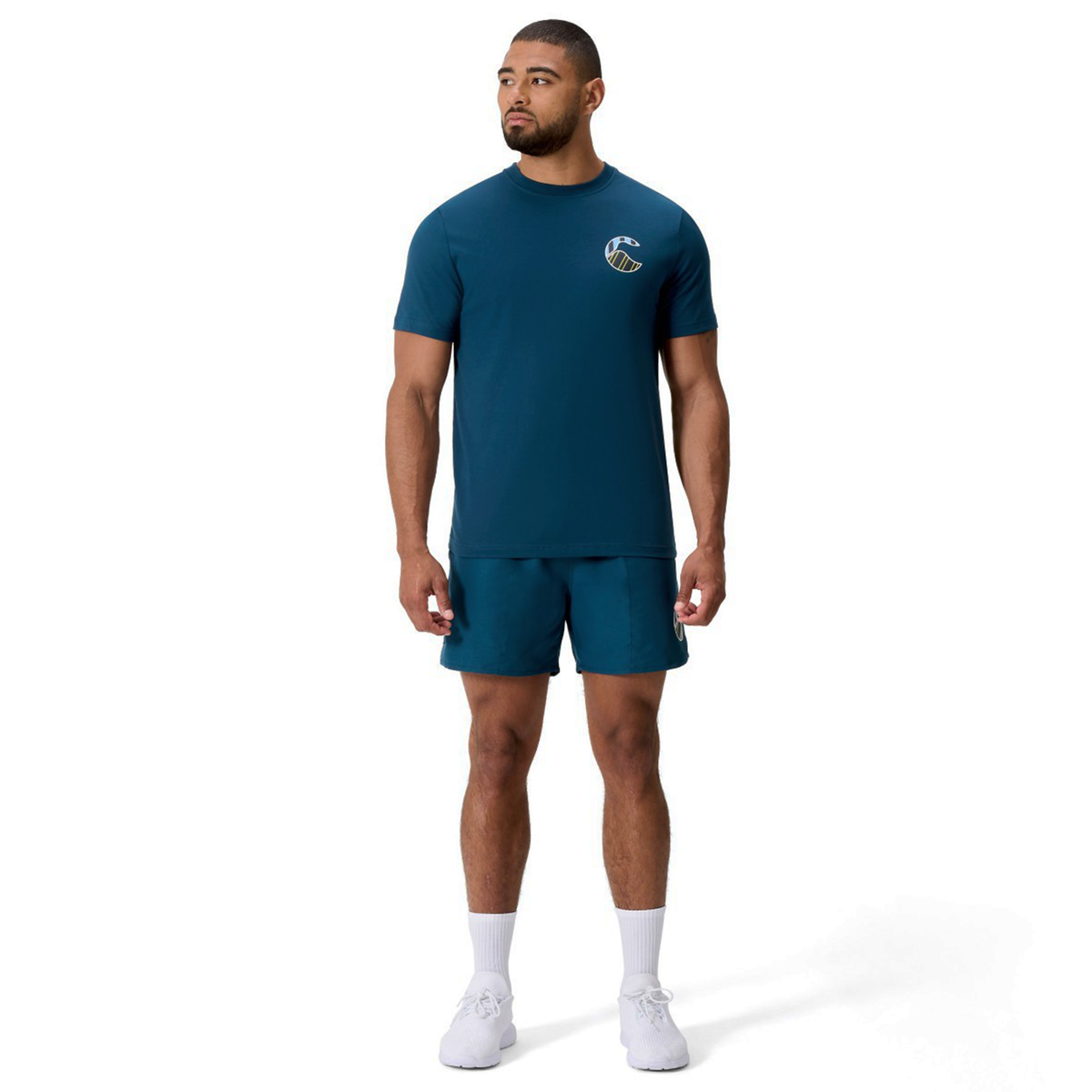 A man faces forward wearing a teal Canterbury Uglies Logo T-Shirt, matching shorts, white crew socks, and white athletic shoes against a plain white background.