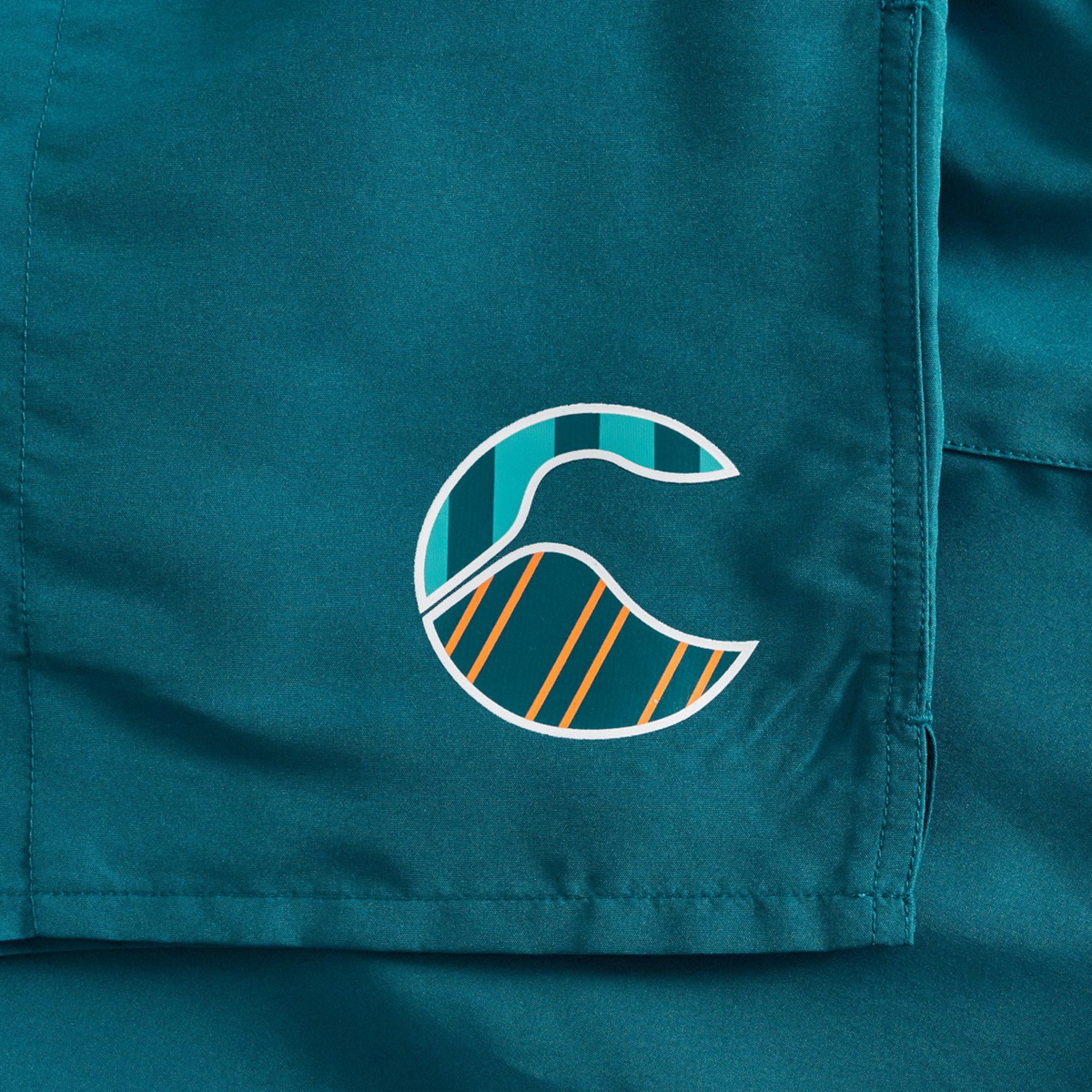 A teal fabric featuring Canterbury’s stylized white, teal, and orange wave-patterned logo with curved and diagonal lines, inspired by the iconic Uglies Logo Tactic Shorts by Canterbury.
