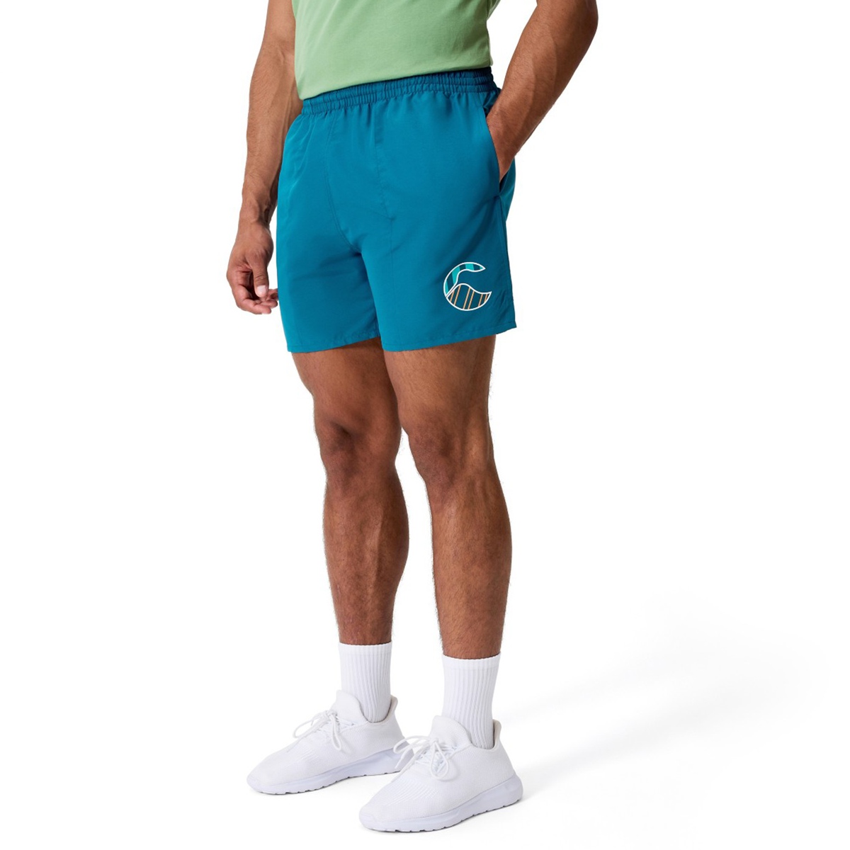 A person in a green shirt, white socks, white sneakers, and Canterbury’s Uglies Logo Tactic Shorts stands against a plain white background.