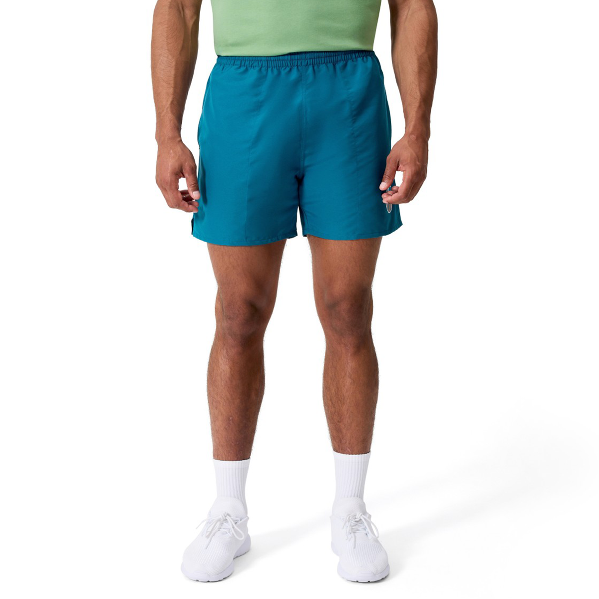 A person wearing a green shirt, Canterbury Uglies Logo Tactic Shorts, white crew socks, and white sneakers stands against a white background.