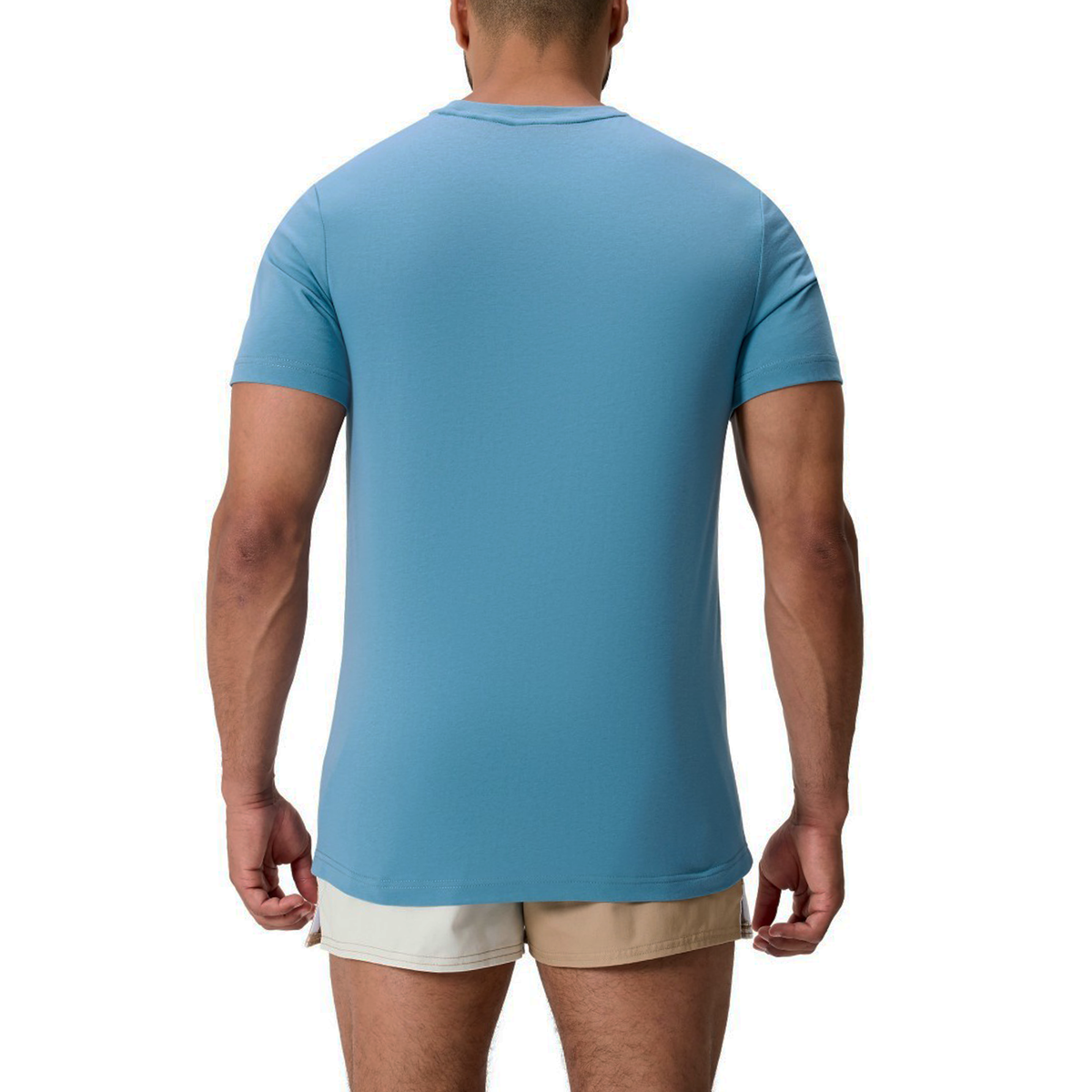 A man with his back to the camera wears the light blue Fundamentals CCC Logo T-Shirt by Canterbury and beige shorts, set against a white background.