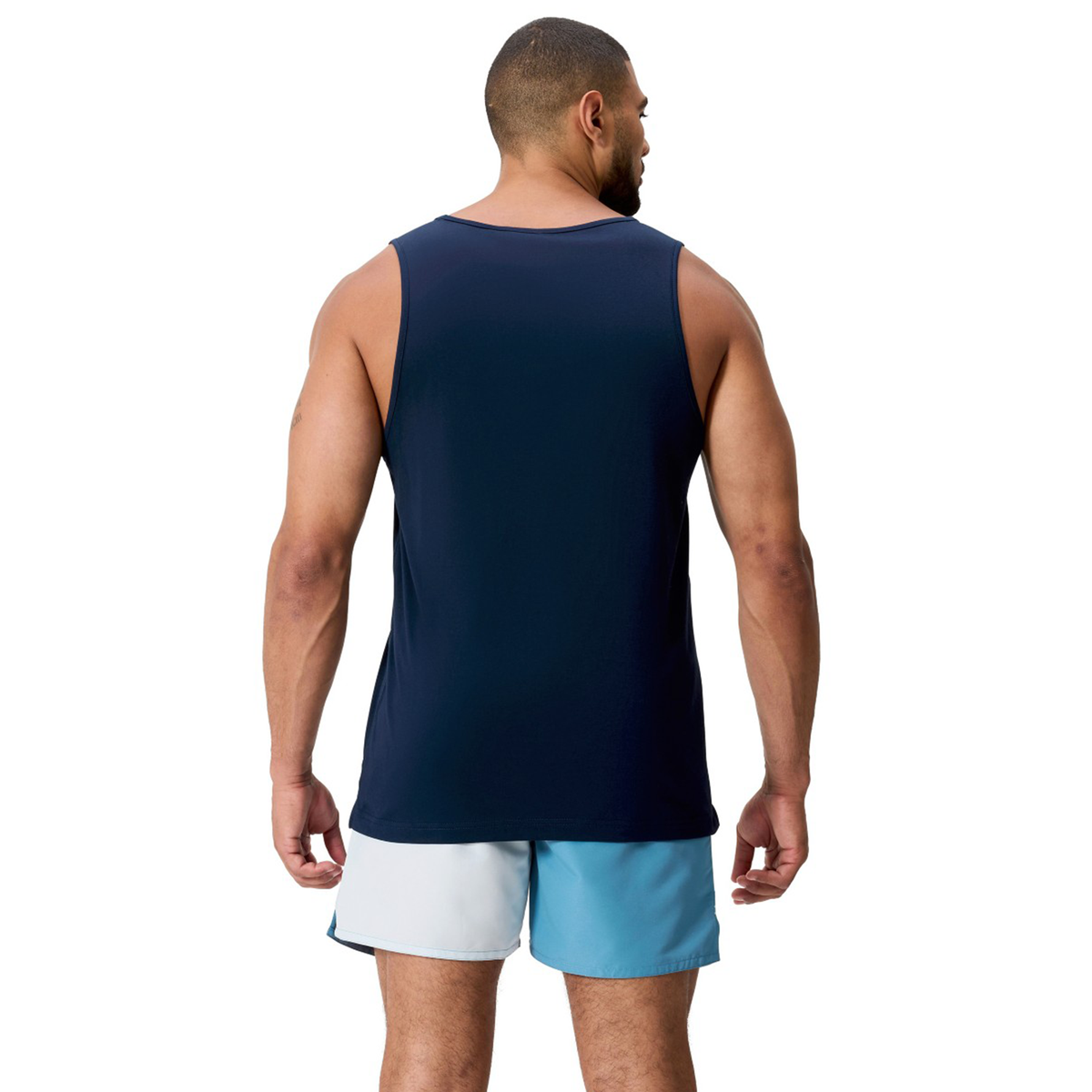 A man faces away from the camera, wearing the Canterbury Fundamentals CCC Logo Tank (H225) and light blue shorts with a dark waistband—ideal for honing training basics.