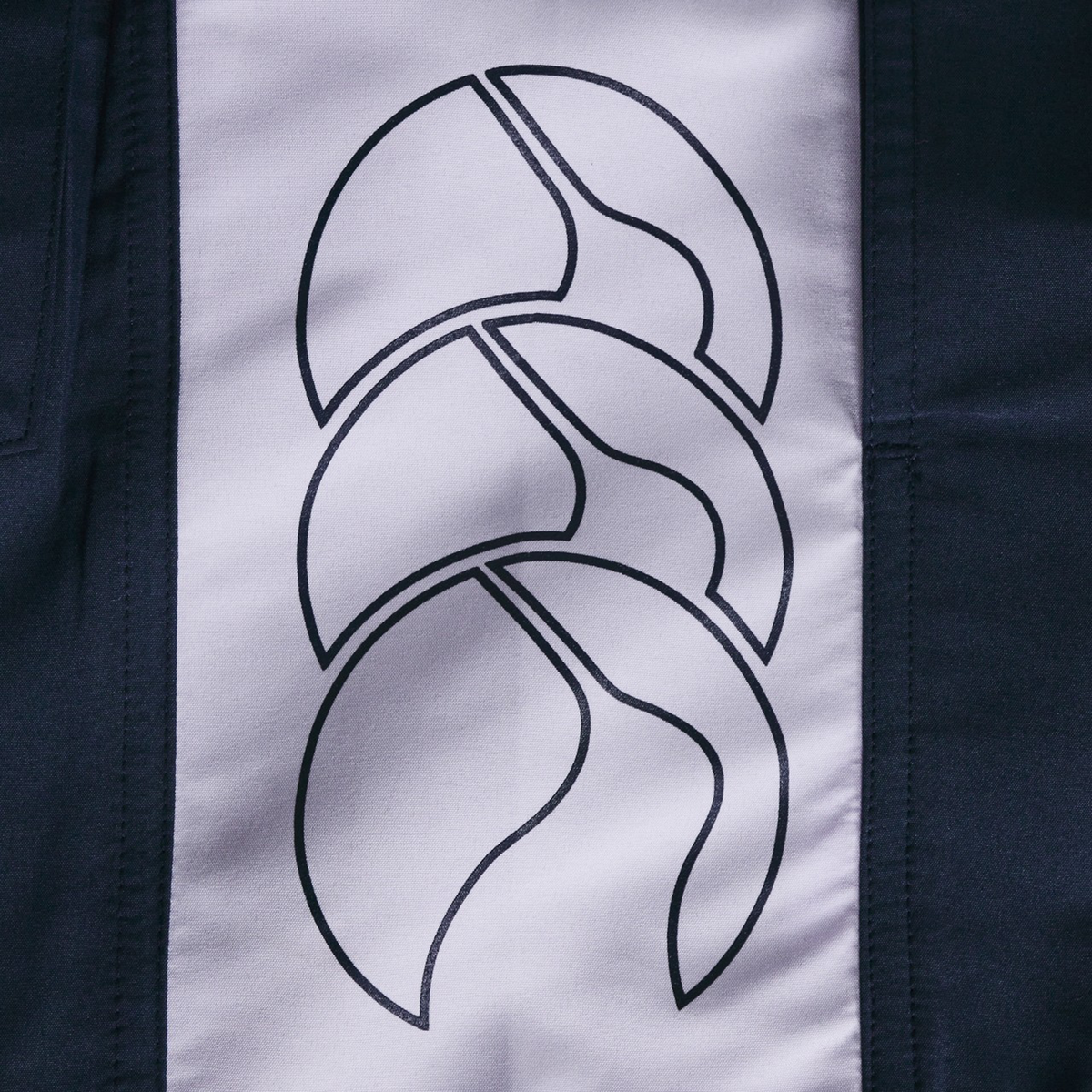 A close-up of a fabric panel from Canterbury’s Women's Fundamentals 5" Panel Tactic Shorts, showcasing three overlapping abstract lines with bold dark and light color contrast.