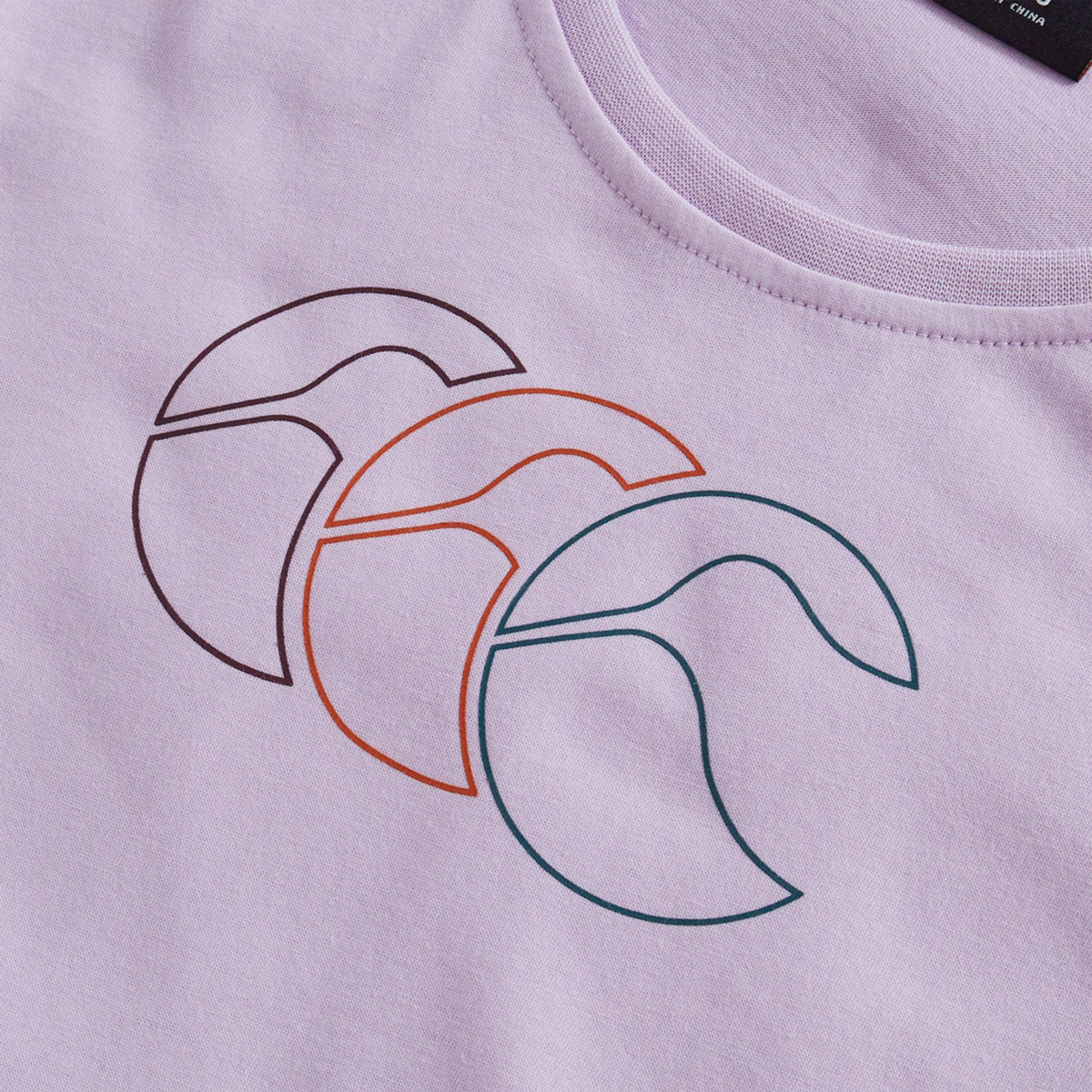 The Women's Fundamentals CCC Logo T-Shirt by Canterbury features a lavender base with three overlapping abstract circles in black, orange, and teal—a stylish choice for women's sportswear or rugby fans.