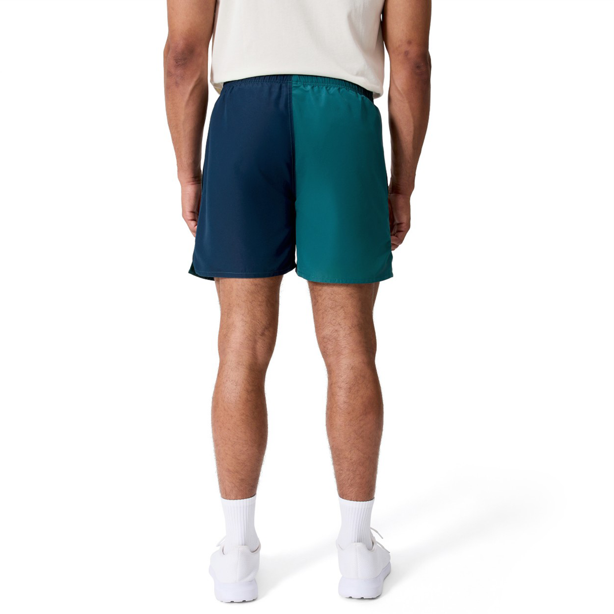 A man is seen from the back wearing Canterbury Fundamental Harletic 3" Shorts, a light shirt, white socks, and white athletic shoes against a plain white backdrop.