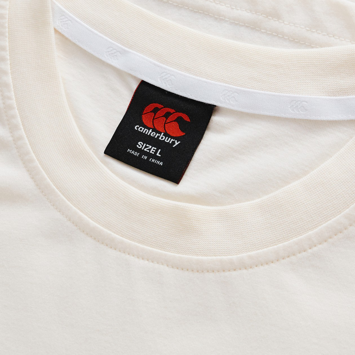 Close-up of the Force CCC T-Shirt by Canterbury in cream, featuring an athletic cotton-blend fabric, detailed collar, and a black label showing size L with "Made in China" text.