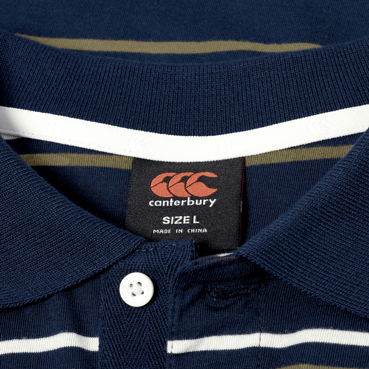 Close-up of the Canterbury Yarn Dye Stripe Polo in navy blue, featuring a classic rugby polo collar, a white button, and a “Canterbury Size L Made in China” label.