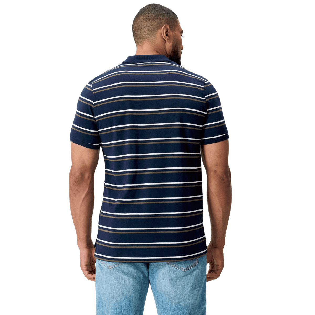 A man is seen from behind, dressed in a Canterbury Yarn Dye Stripe Polo by Canterbury in navy blue with white horizontal stripes, paired with light blue jeans, set against a plain white background.