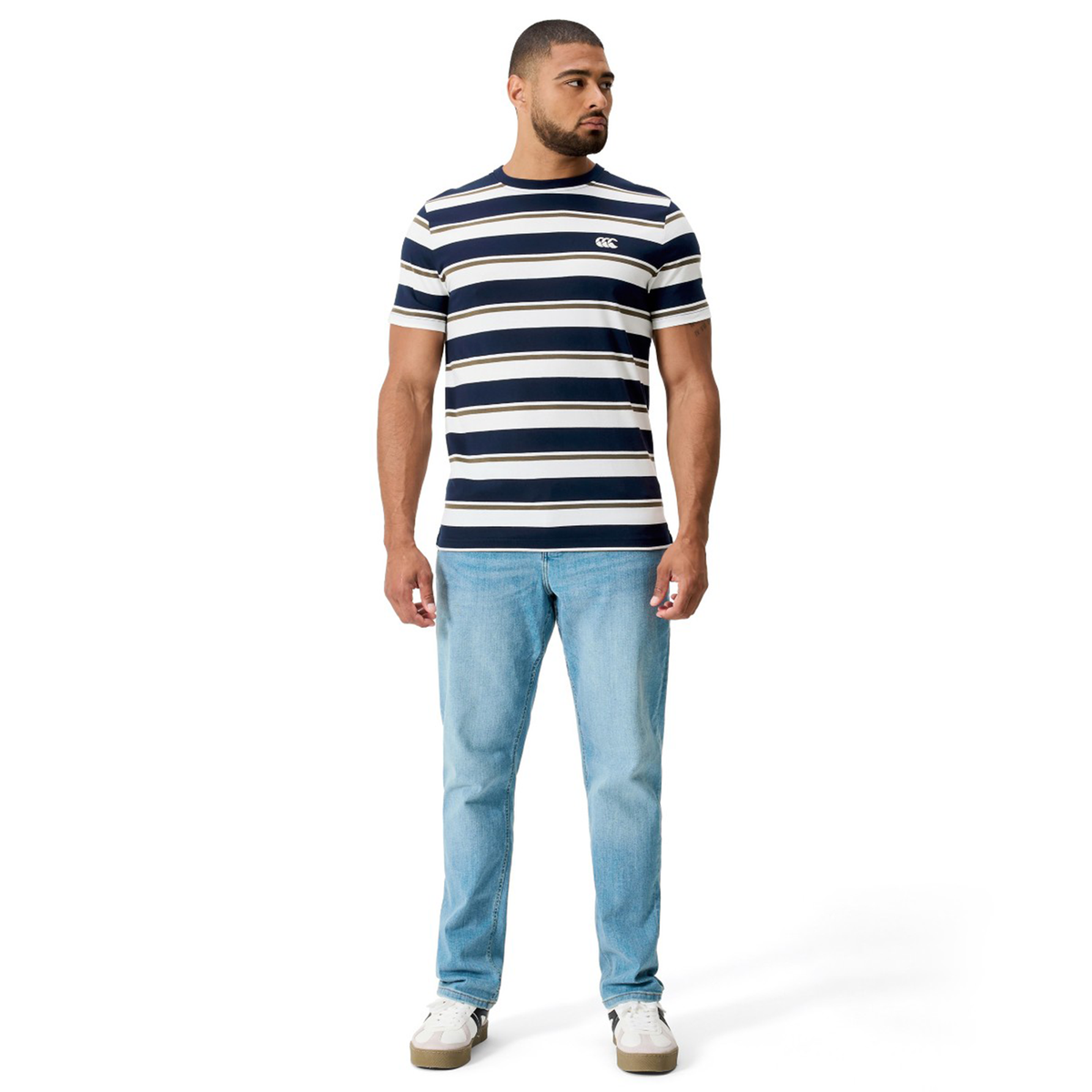 A man faces forward wearing the Canterbury Fundamental Yarn Dye Stripe T-Shirt in navy and white, paired with light blue jeans and white sneakers against a plain white background.