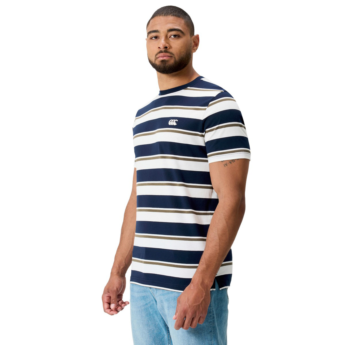 A man in the Canterbury Fundamental Yarn Dye Stripe T-Shirt, featuring navy and white stripes, paired with light blue jeans, stands angled slightly to the side against a white background.