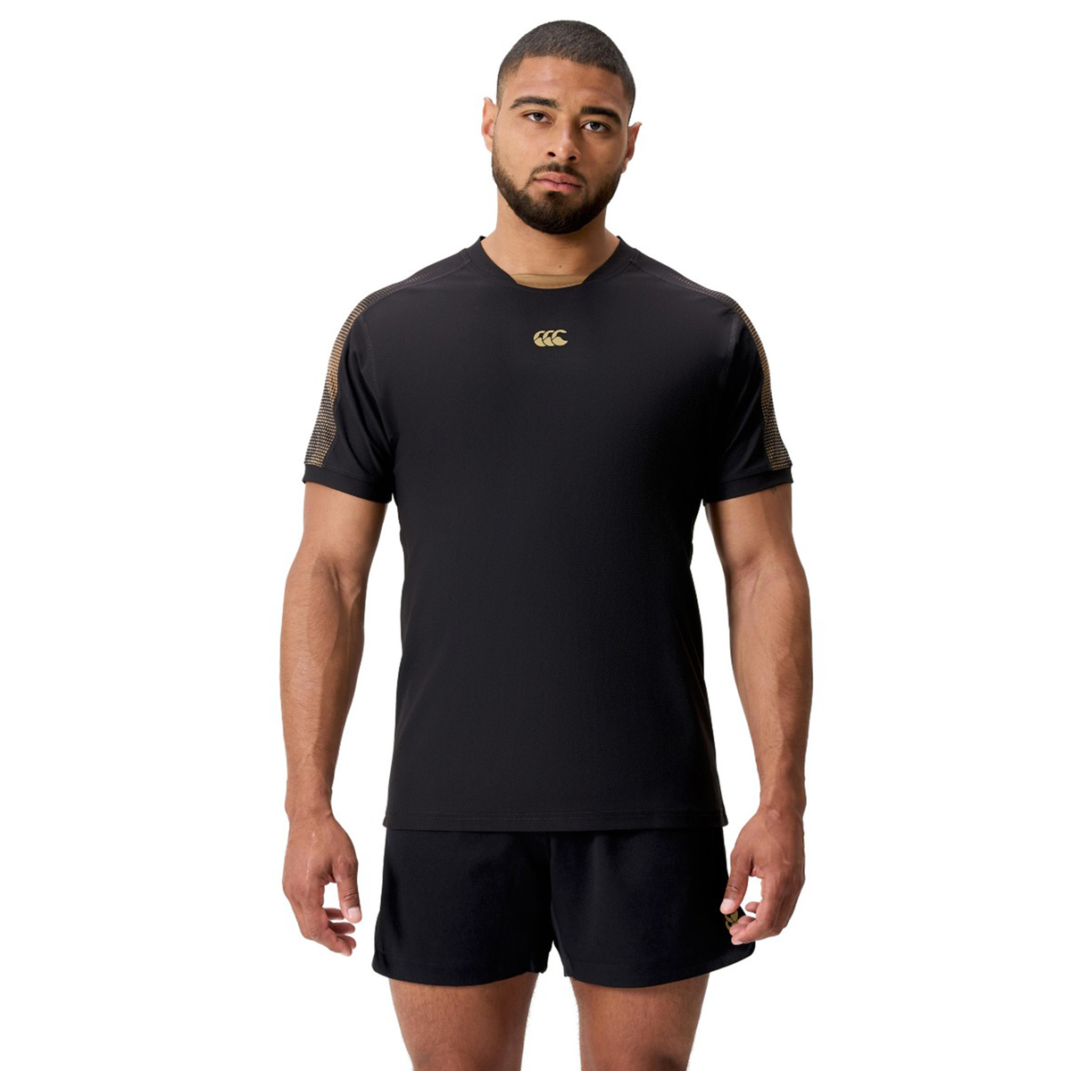 A man wearing the Canterbury Tempo+ Drill Top and matching black shorts stands facing forward against a plain white background.