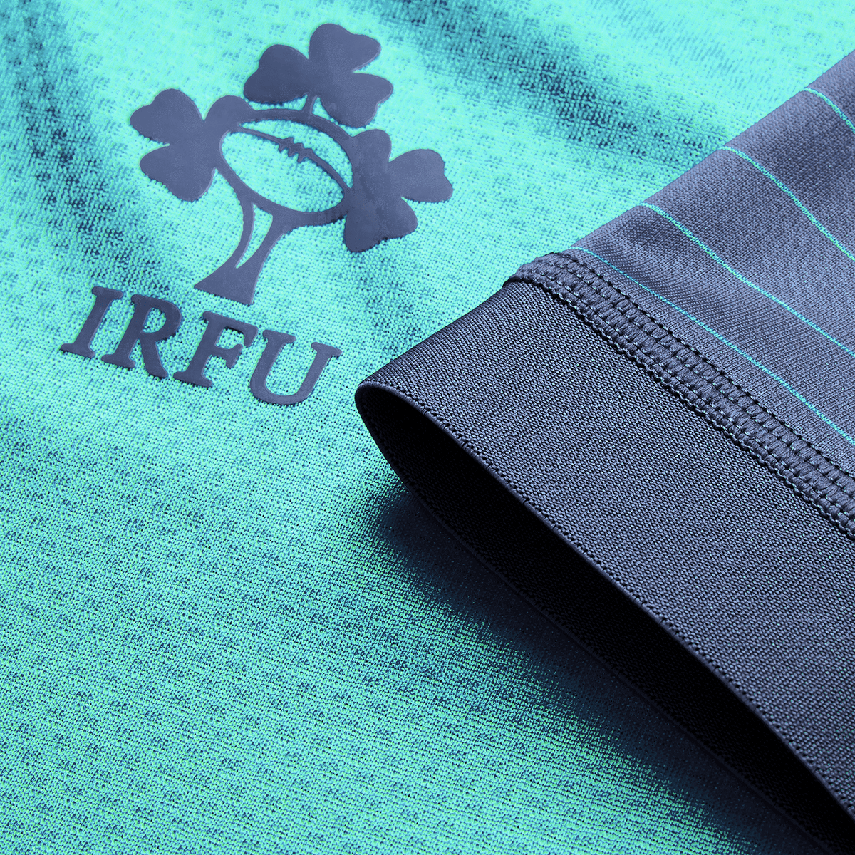 Close-up of the Ireland 26/27 Summer Tour "Baltic" Training Test Jersey by Canterbury in teal, featuring the IRFU shamrock logo and blue-green sleeve stripes—ideal for fans supporting Ireland on their summer tour.