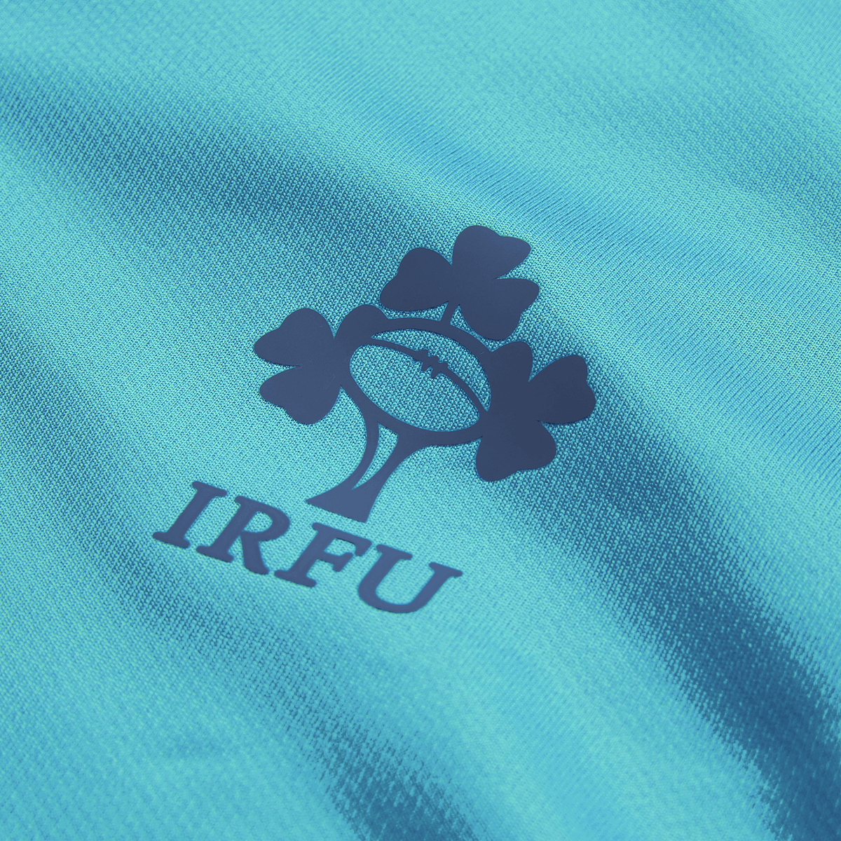 Close-up of the Ireland 26/27 Summer Tour Training Pro Jersey by Canterbury, a blue training top featuring the Irish Rugby Football Union (IRFU) logo with a rugby ball and three shamrocks.