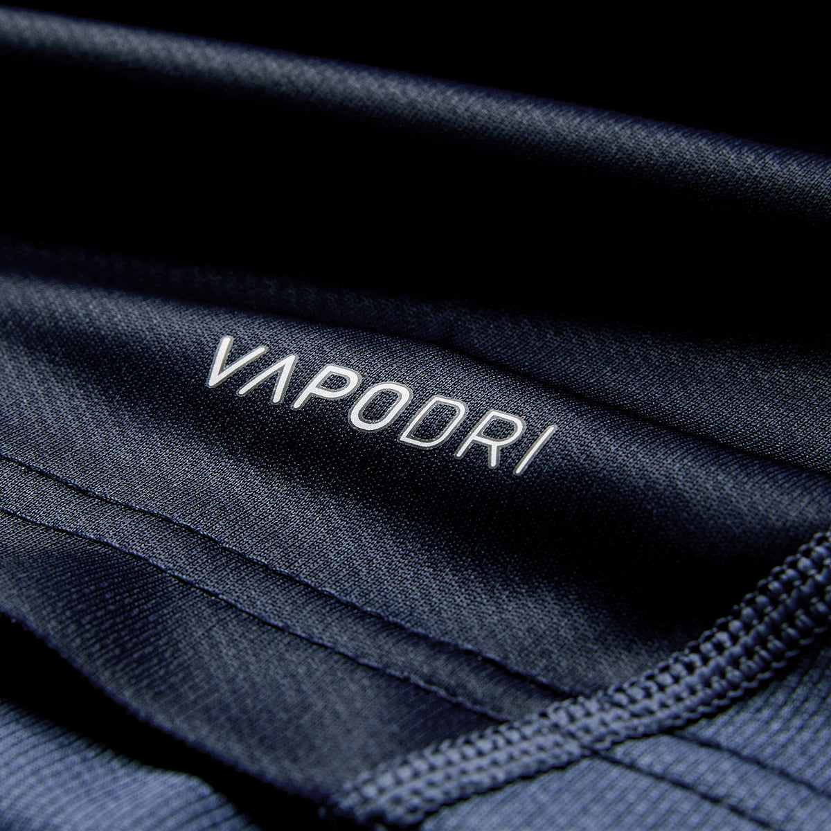 Close-up of dark blue athletic fabric from the Ireland 26 Training Pro Jersey by Canterbury, featuring the word “VAPODRI” printed in white and visible stitching along the edges.