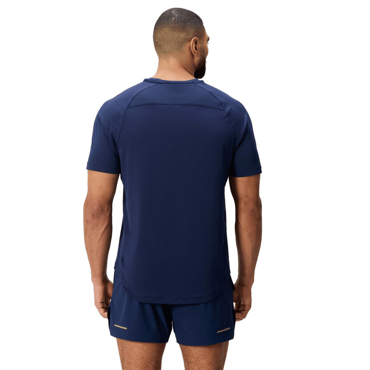 A man faces away from the camera, wearing the Canterbury Everest Dart Tech T-Shirt by Canterbury in navy blue, paired with matching shorts. The moisture-wicking polyester set is displayed against a white background.