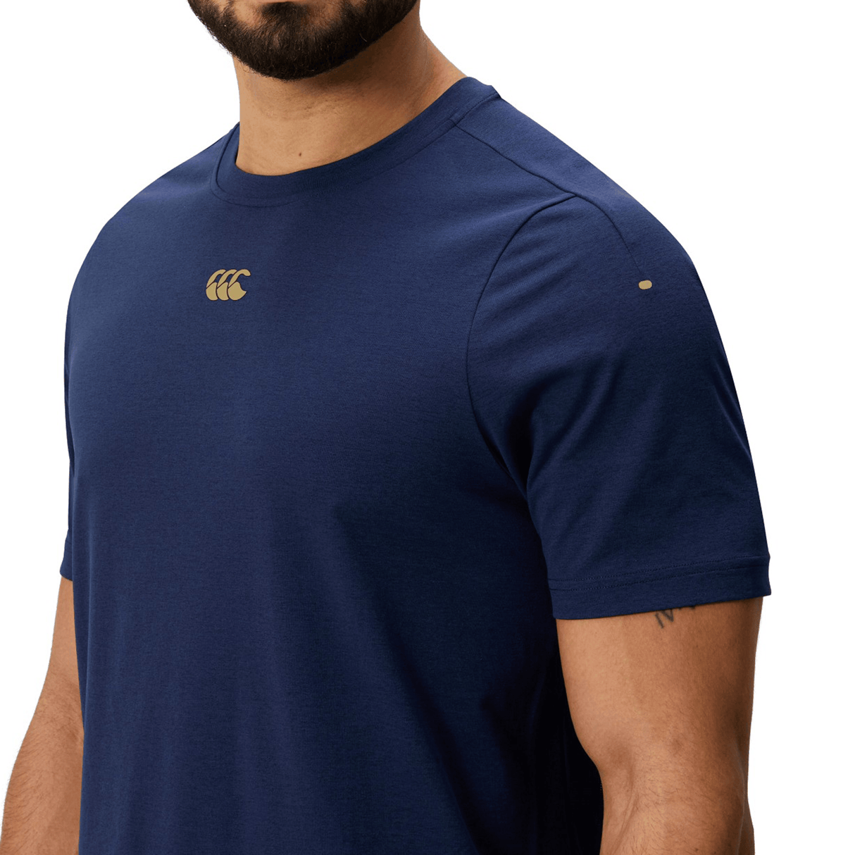 Man wearing the Canterbury Everest Dart Tech T-Shirt by Canterbury, a plain navy blue quick-drying tee featuring a small logo on the chest and an additional small mark on the sleeve.