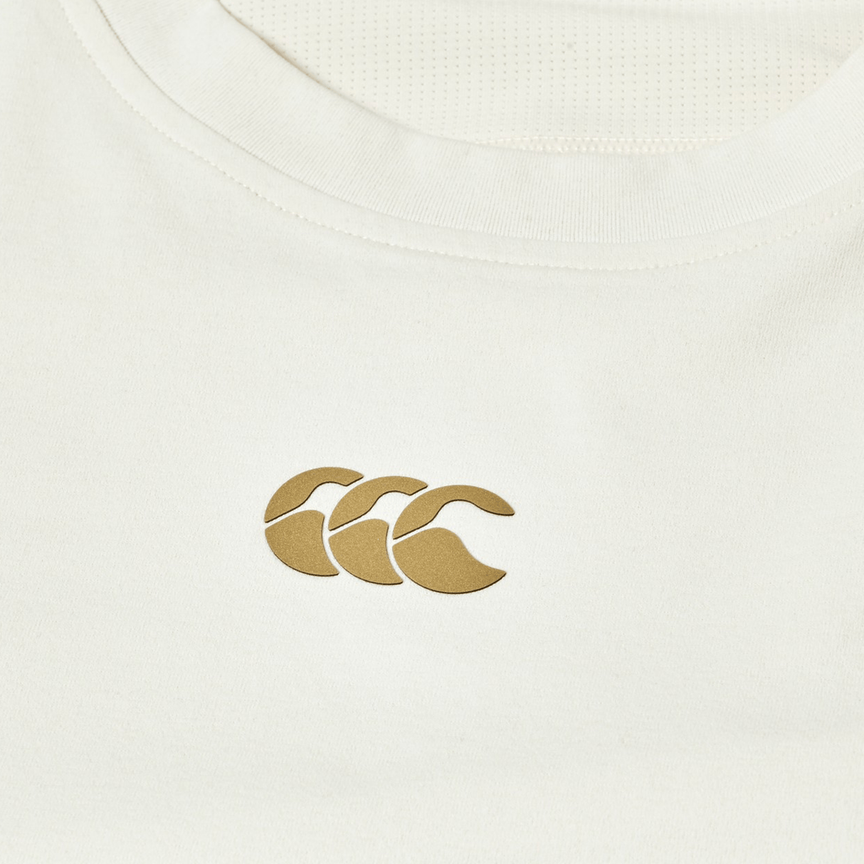 Close-up of the Canterbury Everest Dart Tech T-Shirt, a white, breathable workout top with a gold Canterbury logo of three overlapping C’s on the chest.