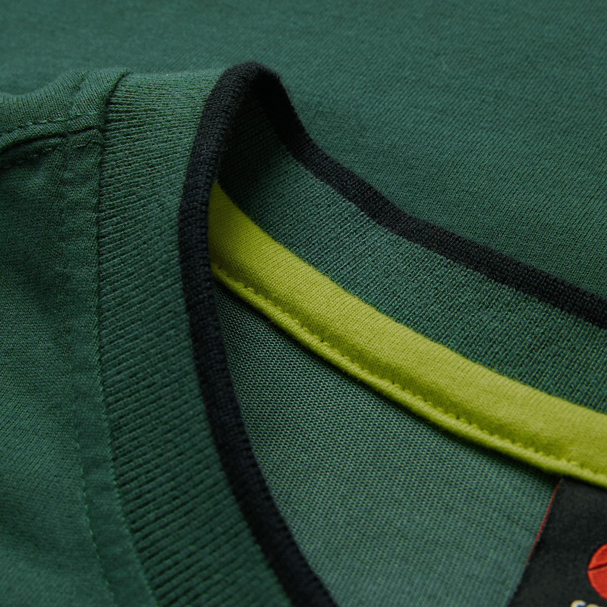 Close-up of the Ireland 26 Team Cotton T-shirt by Canterbury, showing a green collar with a black outer edge and a yellow inner seam detail, inspired by the iconic Canterbury Ireland shirt.