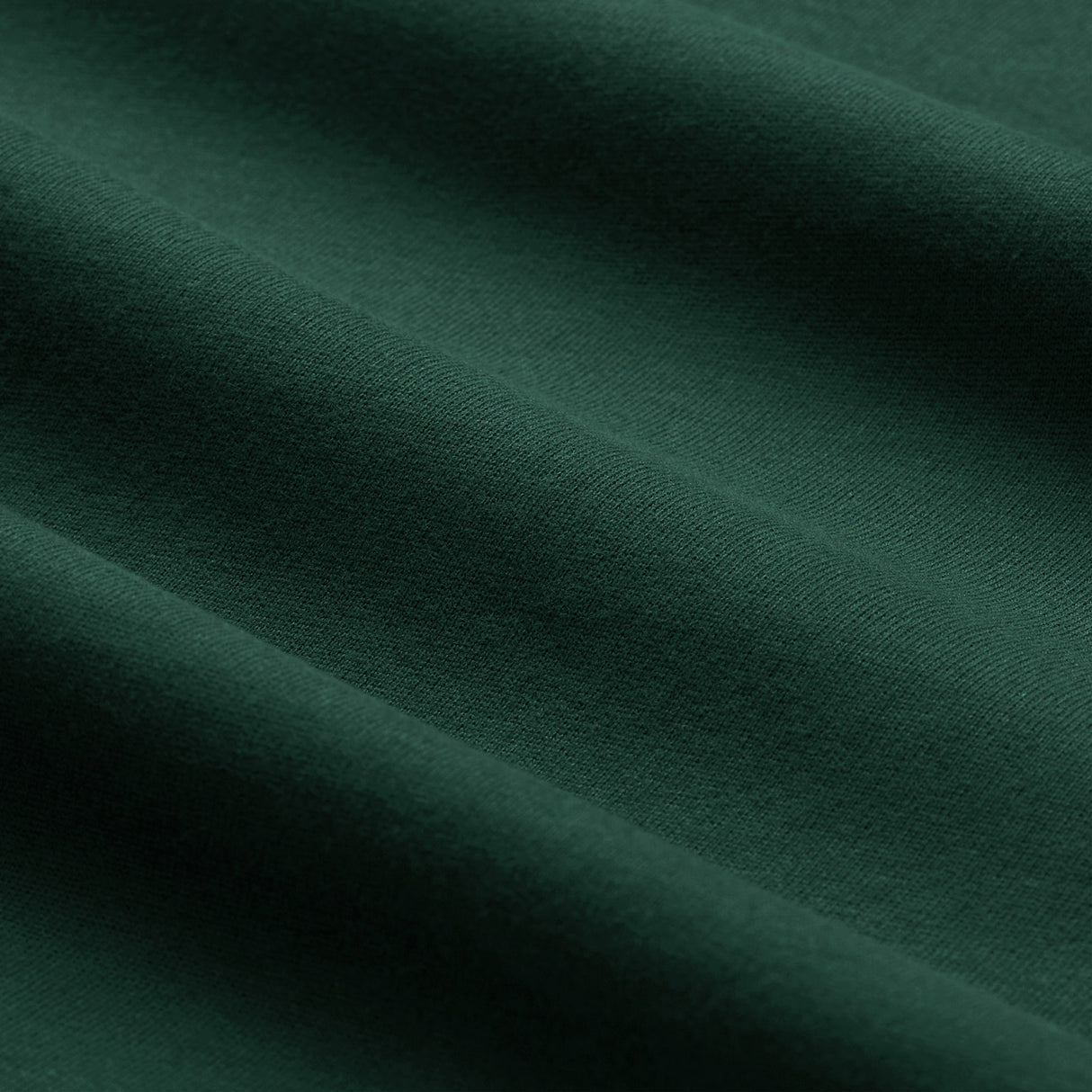 Close-up of dark green fabric with a visible soft texture and gentle horizontal folds, reminiscent of the premium material used in the Ireland 26 Team Cotton T-shirt by Canterbury.
