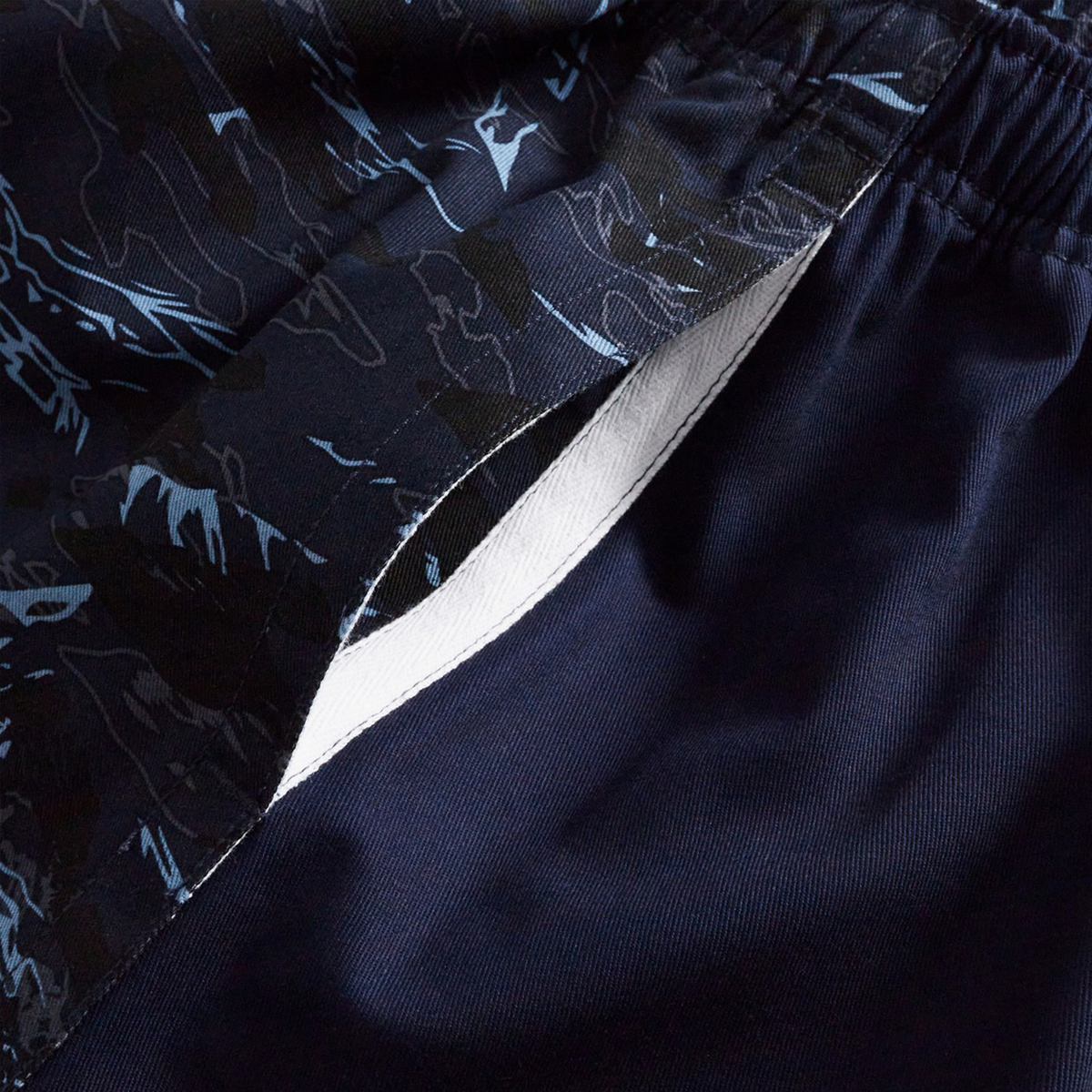 Close-up of Canterbury’s Force Harlequin Drill Shorts in navy blue, showing a white inner lining, open side pocket, and a black and blue abstract-patterned waistband.