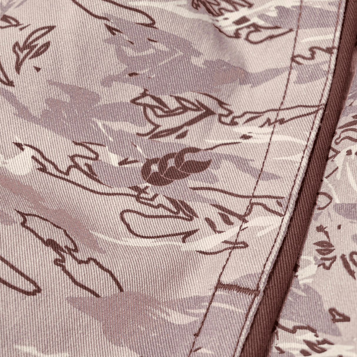 Close-up of Canterbury Force Harlequin Drill Short fabric by Canterbury, featuring a brown and beige camouflage pattern with visible seam stitching, reflecting classic military-inspired utility short design.