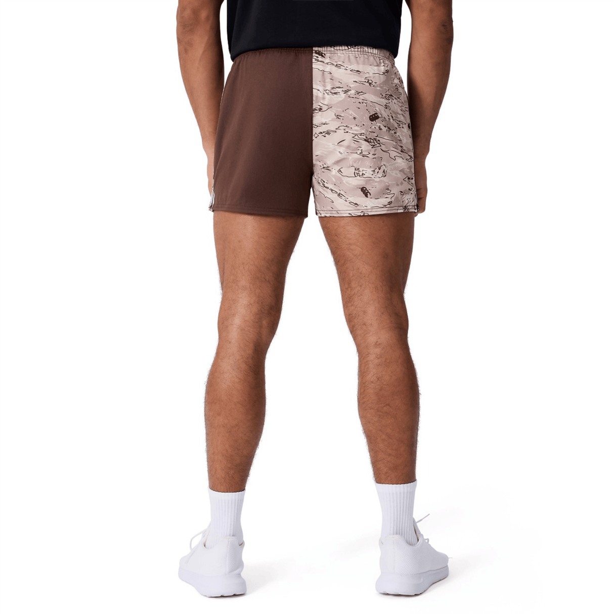 A person wearing a black shirt, white sneakers, and Canterbury Force Harlequin Drill Shorts by Canterbury, which have one brown leg and one beige camo leg, viewed from the back.