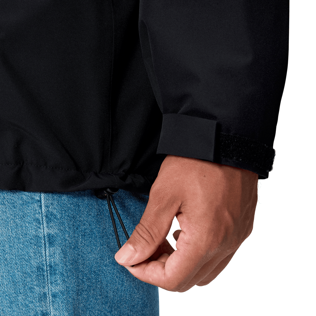 A person in blue jeans uses one hand to tighten the hem drawstring of a Canterbury Ireland 25/26 Water Resistant Insulated Jacket.