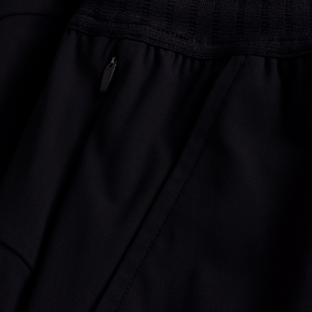 Close-up of the black Ireland 25/26 Gym Training Short by Canterbury, showcasing a zippered pocket with metallic pull and detailed stitched seams.