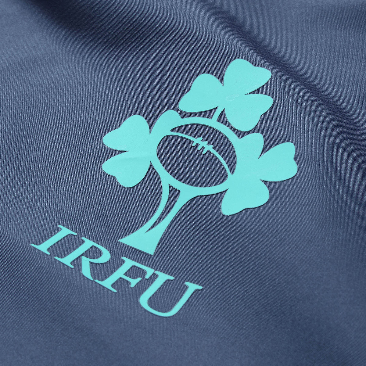 Close-up of the Irish Rugby Football Union (IRFU) logo, featuring a rugby ball and three shamrocks, printed on dark fabric—highlighting the quality craftsmanship of the Ireland 26 Legends 1/4 Zip Jacket by Canterbury.