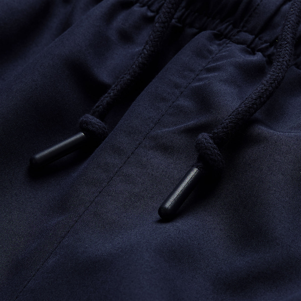 Close-up of dark blue fabric with an elastic waistband and two black drawstrings featuring plastic tips, highlighting the detail found in the Ireland 26 Legends 32″ Trackpant by Canterbury.