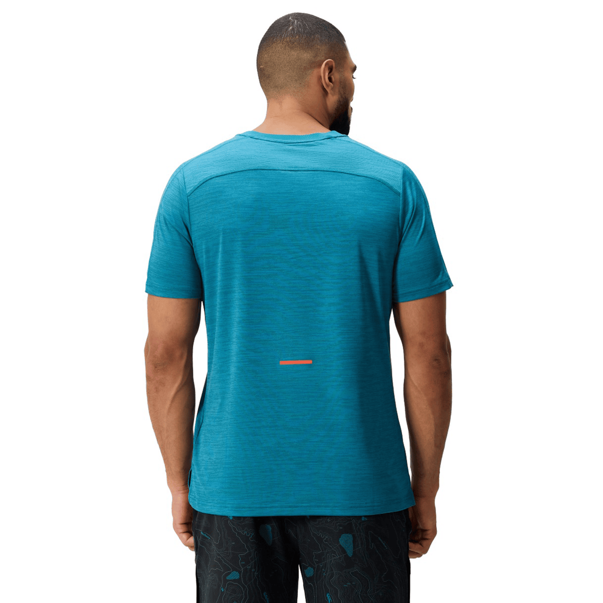 A man wearing a Canterbury Tempo Relaxed T-Shirt is shown from the back in teal and black patterned shorts against a plain white background.