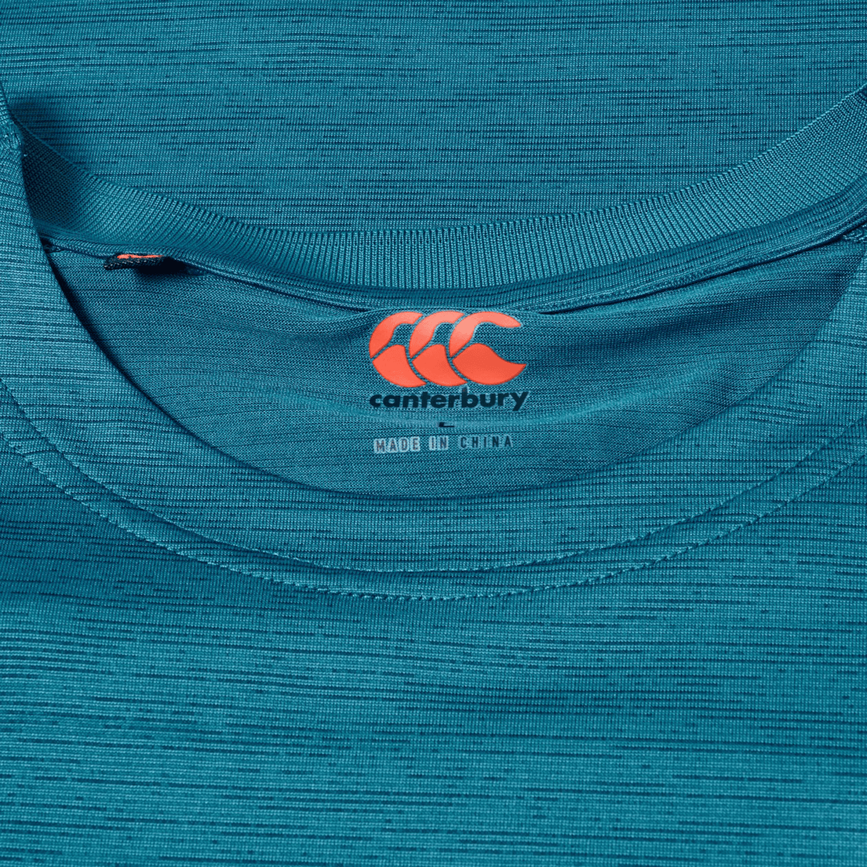 Close-up of the Canterbury Tempo Relaxed T-Shirt in blue, featuring the Canterbury logo and "Made in China" label inside the collar, made from breathable fabric for comfort and performance.