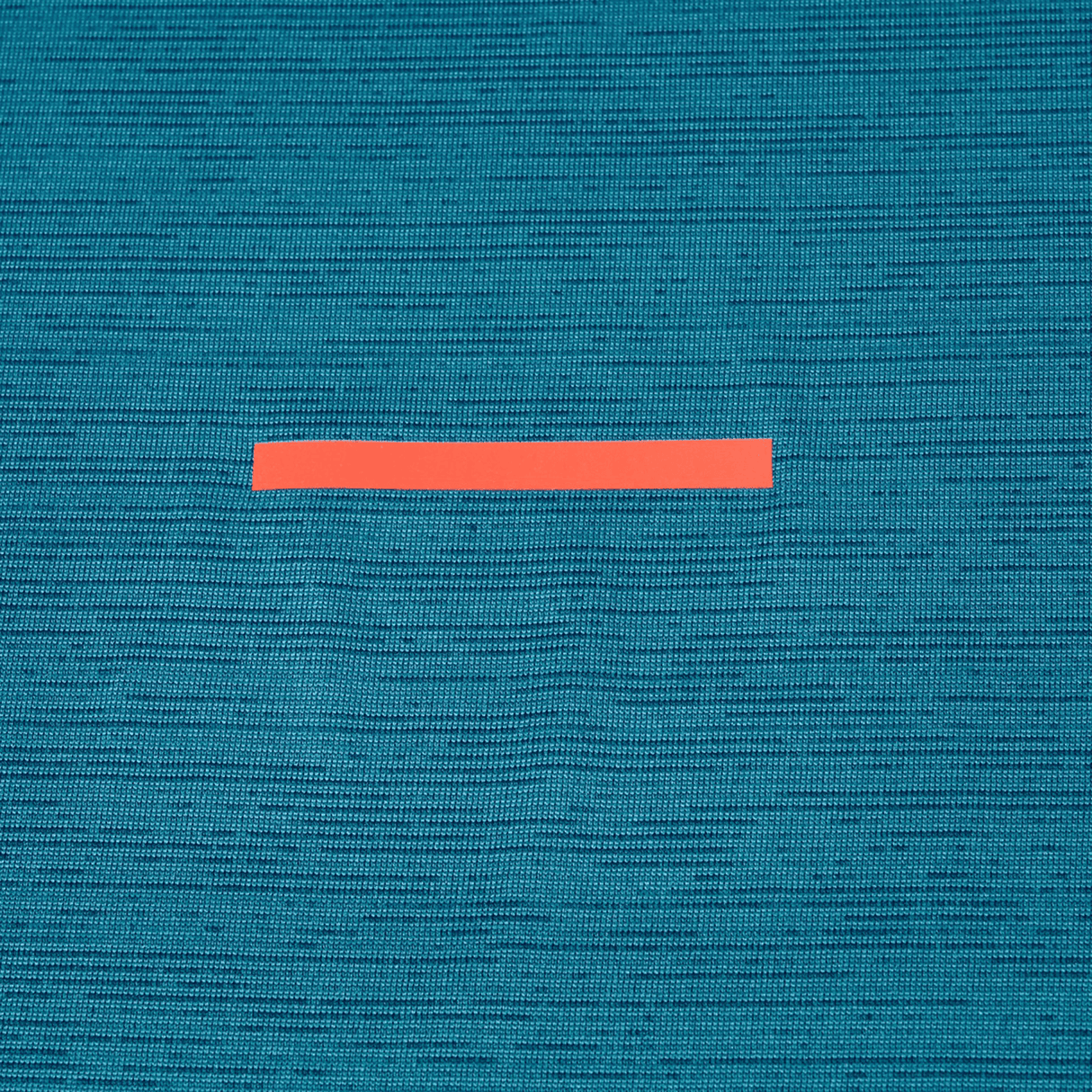 A single red strip of tape rests on textured teal fabric, echoing the breathable material of the Canterbury Tempo Relaxed T-Shirt by Canterbury—ideal for a performance-ready style.