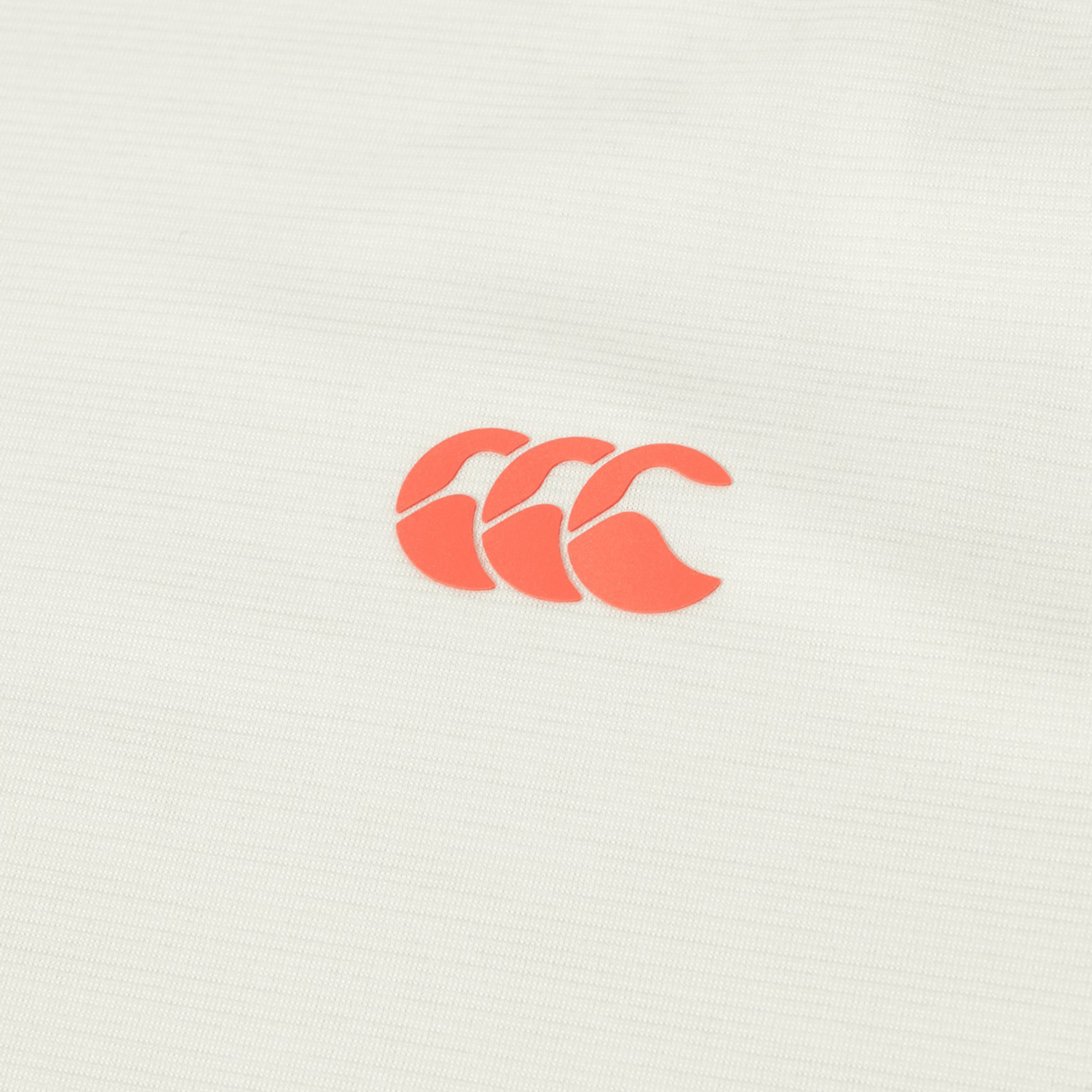 A close-up of the Canterbury Tempo Relaxed T-Shirt shows a red Canterbury logo with three overlapping "C" shapes on white, crafted from breathable fabric for a performance-ready look.