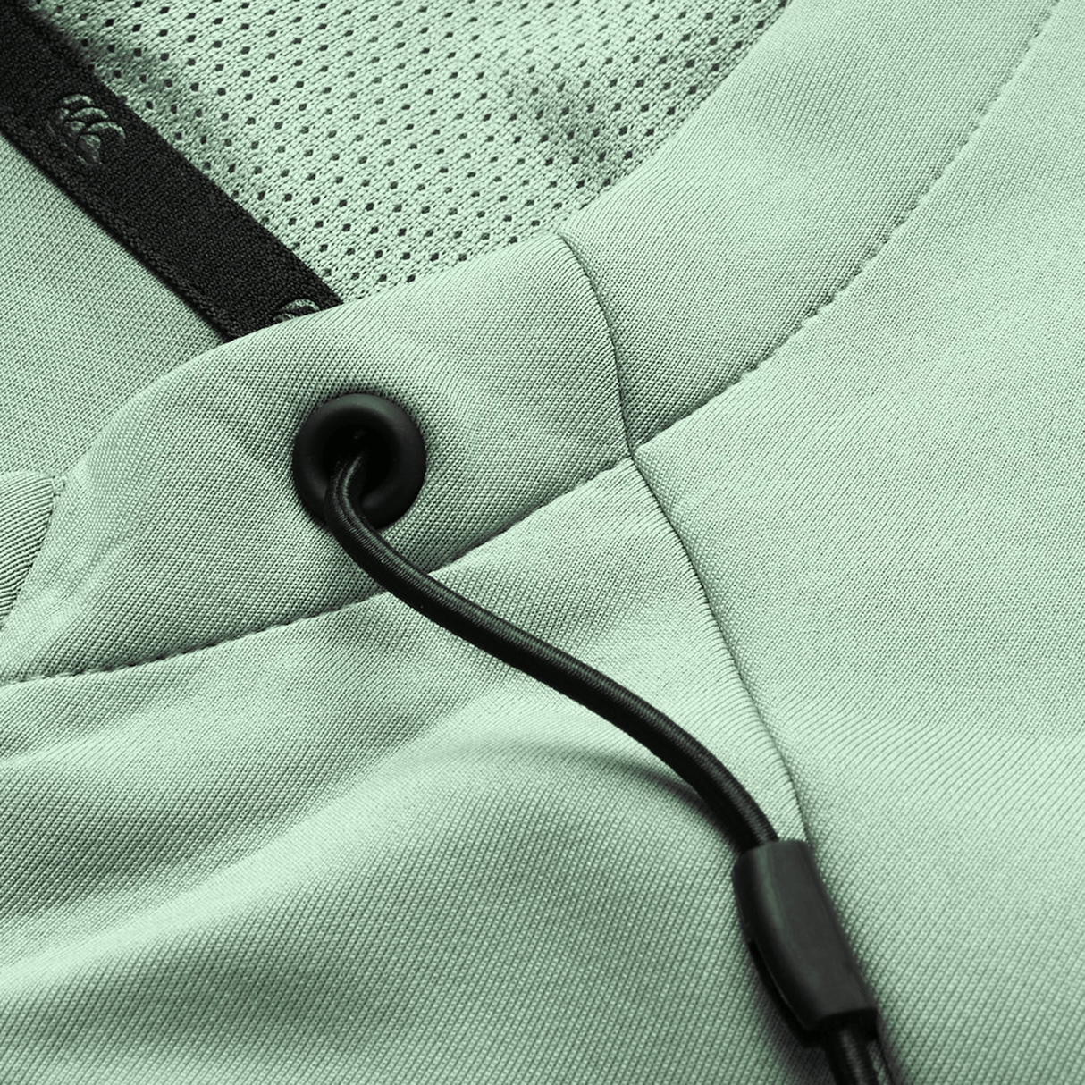 Close-up of the Canterbury Everest Zip Thru Hoodie in light green, featuring black drawstrings with metal grommets, mesh lining, and detailed stitching—a Canterbury performance hoodie blending comfort and style.