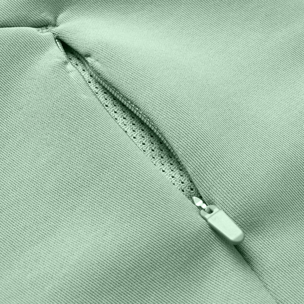 Close-up of a Canterbury Everest Zip Thru Hoodie pocket in light green by Canterbury, showing a partially open zipper and the inner lining.