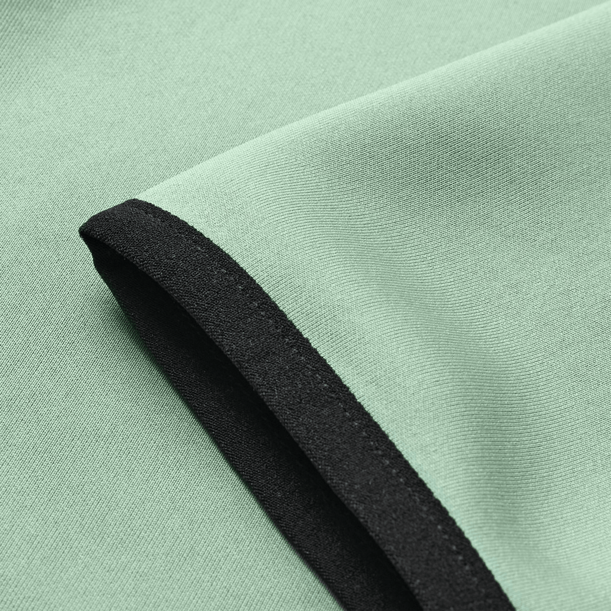 Close-up of the Canterbury Everest Zip Thru Hoodie fabric in light green, showing a folded edge and black trim along the hem.