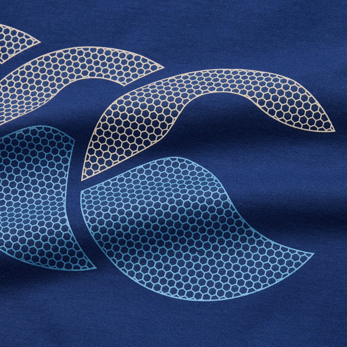 Close-up of the Canterbury Fundamentals T-shirt fabric in blue, featuring abstract honeycomb-patterned shapes in light beige and blue tones printed on the surface—a perfect detail for fans of athletic casual wear from Canterbury.