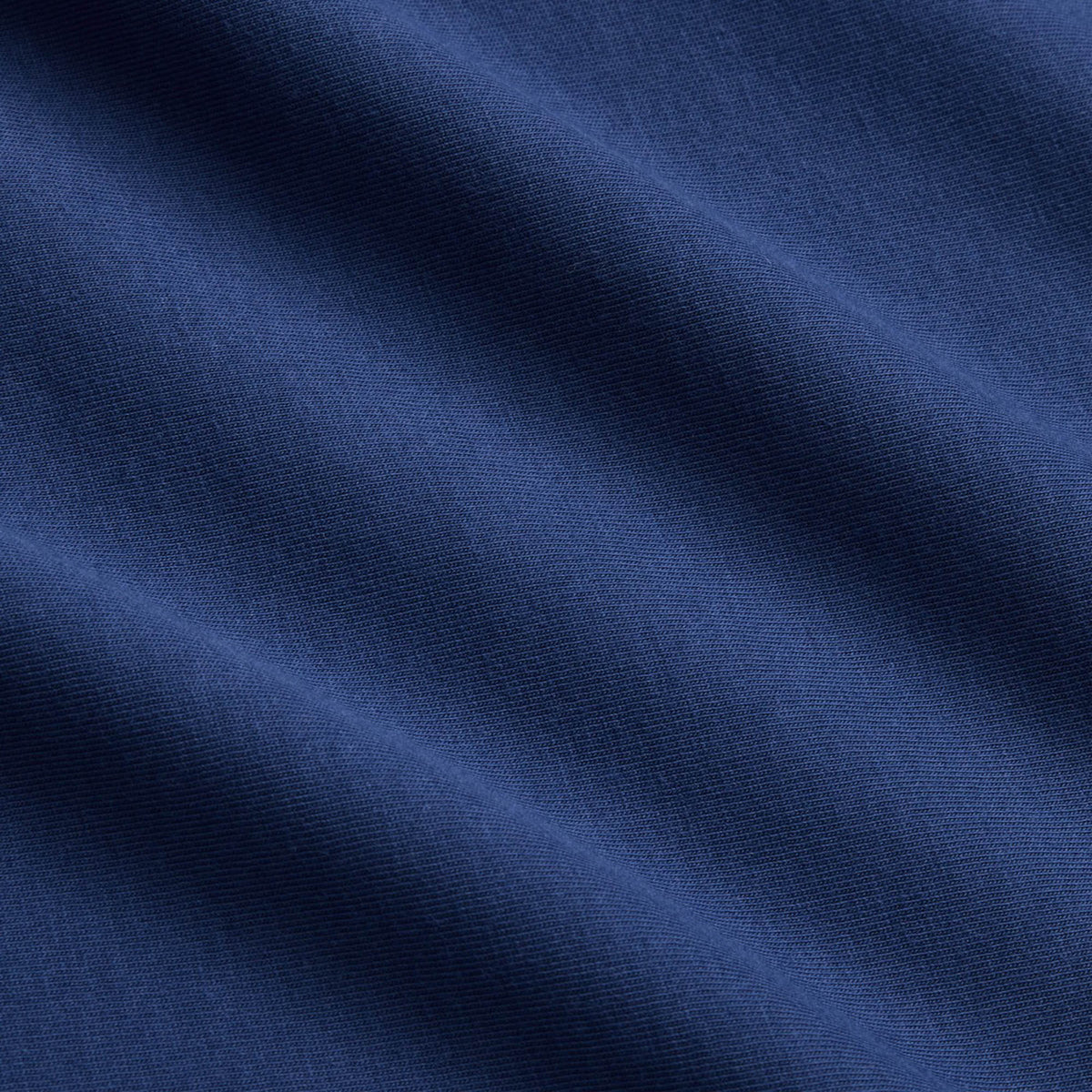 Close-up of blue fabric with visible diagonal folds and fine texture, highlighting the weave and subtle shading—characteristic of an athletic casual wear piece such as the Canterbury Fundamentals T-shirt by Canterbury.