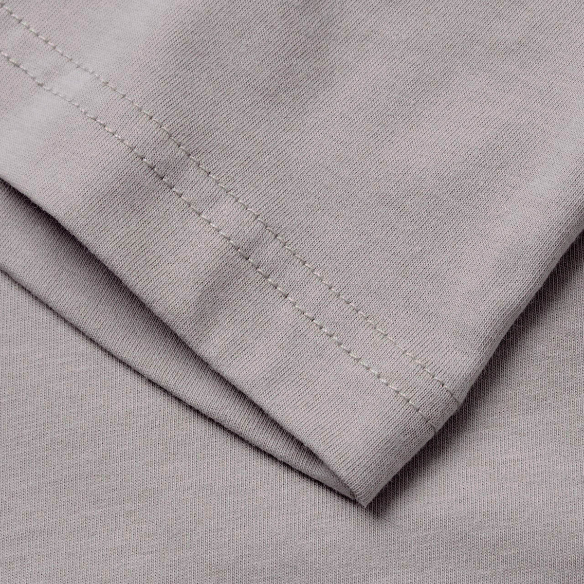 Close-up of a light gray fabric with visible stitching along the edge, displaying the texture and seam details characteristic of athletic casual wear, such as the Canterbury Fundamentals T-shirt by Canterbury.