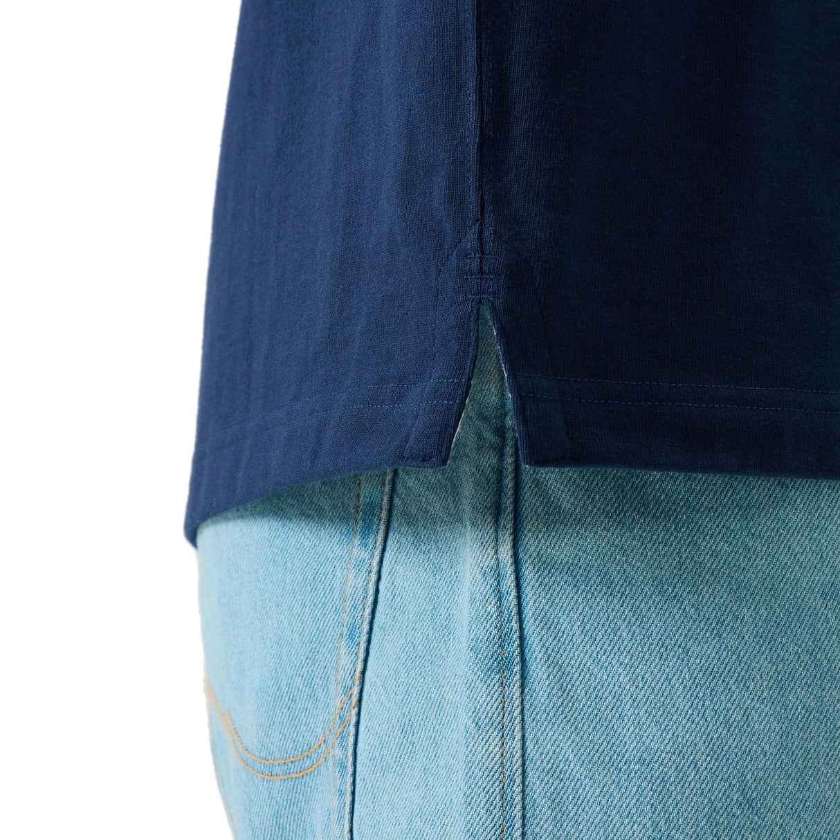 Close-up of the lower side of the Canterbury Stripe Rugby Jersey by Canterbury, featuring a side slit, styled over light blue denim jeans.