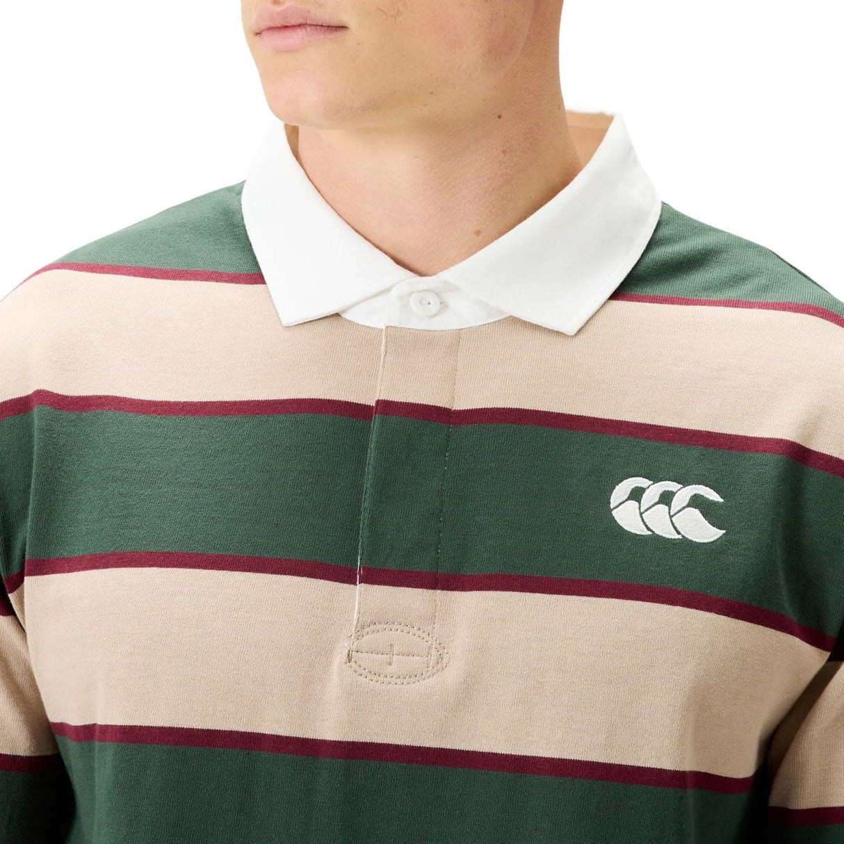 A person wearing the Canterbury Stripe Rugby Jersey by Canterbury, featuring green, beige, and maroon stripes, a white collar, and a white logo on the chest.