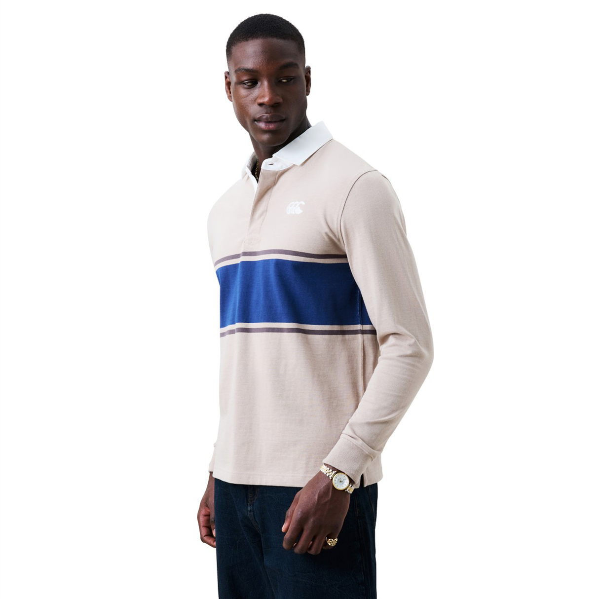 A man wearing a Canterbury Stripe Classic Rugby Jersey by Canterbury, featuring blue and white stripes, stands looking to his left against a plain white background.