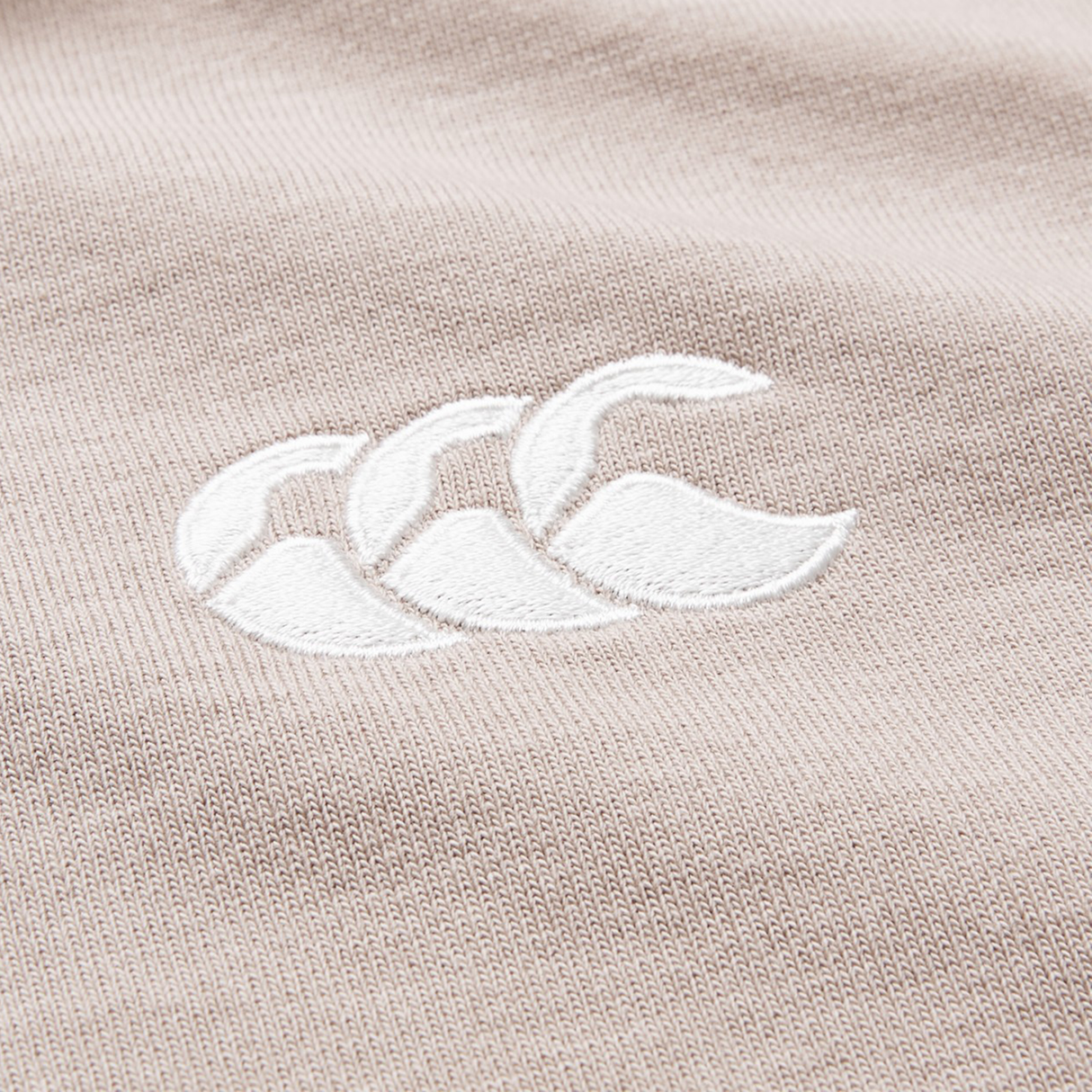 Close-up of a durable cotton blend fabric on the Canterbury Stripe Classic Rugby Jersey by Canterbury, featuring a white embroidered logo with three overlapping curves inspired by the jersey's signature design.