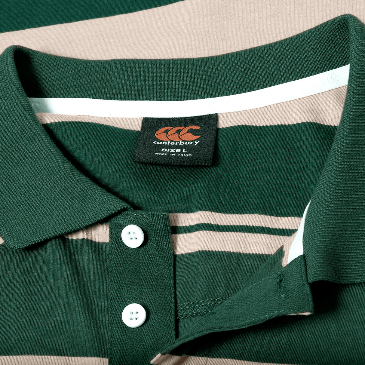 A close-up of the Canterbury Yarn Stripe Polo from Canterbury in green and beige, showcasing its classic rugby style with a detailed view of the collar, buttons, and "2XL" size label.