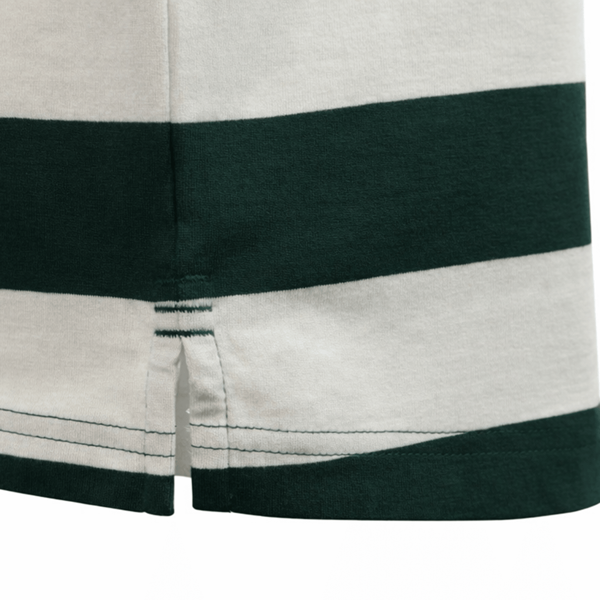 Close-up of the hem on the Canterbury Yarn Stripe Polo by Canterbury in white and dark green, showing a small side slit and visible stitching that emphasize its classic rugby style.