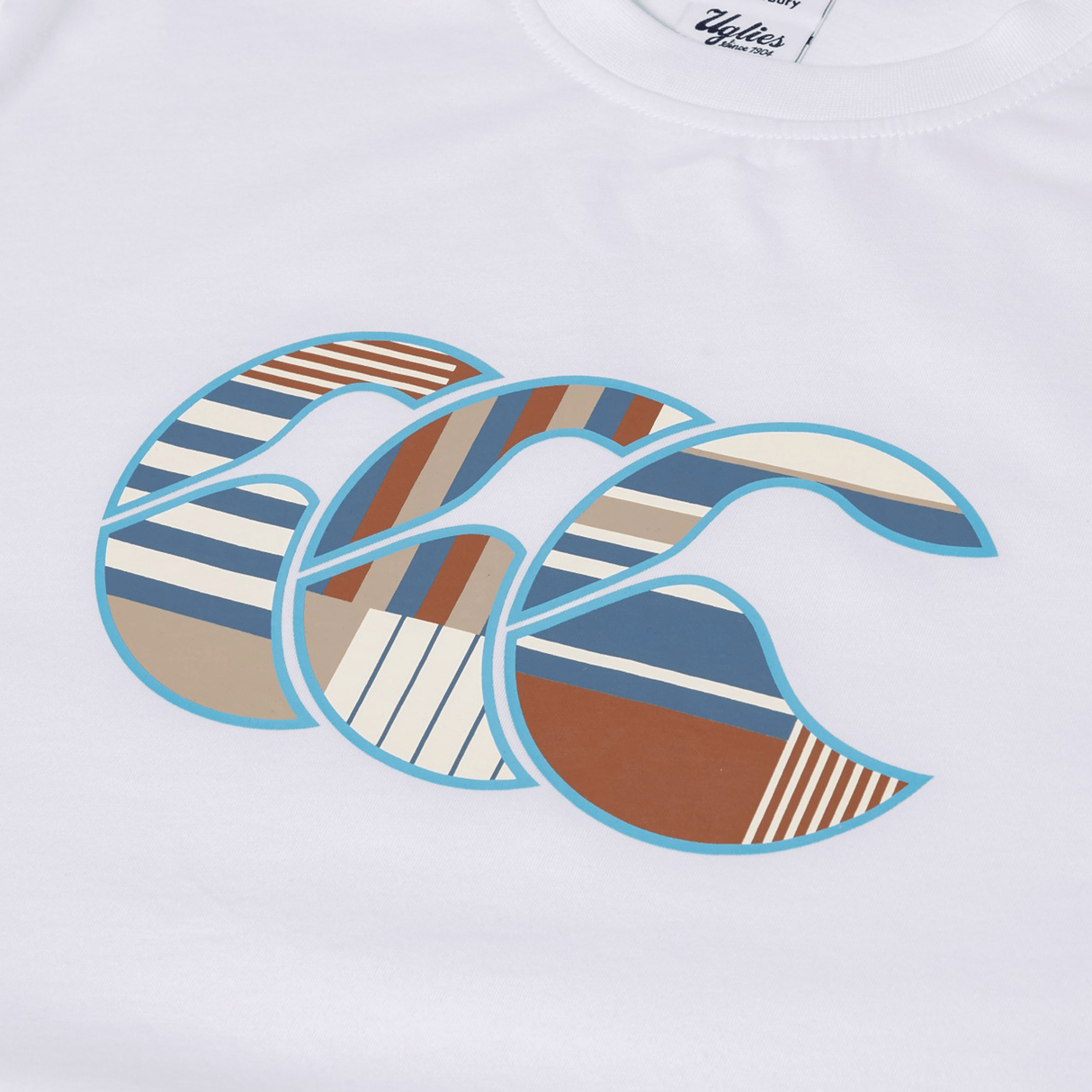 The Canterbury Uglies Logo T-shirt by Canterbury is a white cotton-blend tee with three overlapping stylized “C”s outlined in blue and featuring geometric patterns—ideal for fans of unique logo styles.