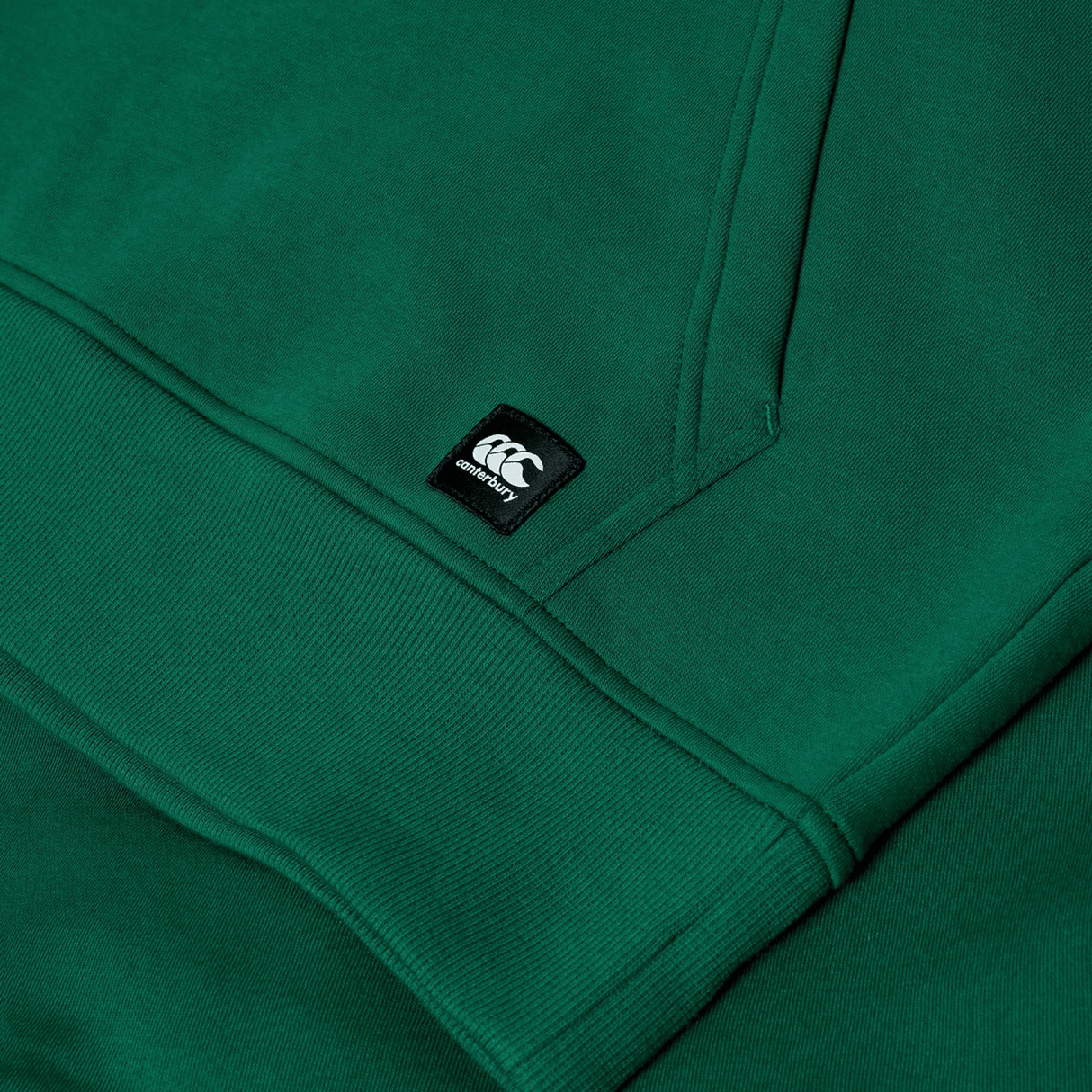 Close-up of the Canterbury Uglies Logo Hoodie in green, featuring ribbed cuffs and a small black and white Canterbury logo tag.