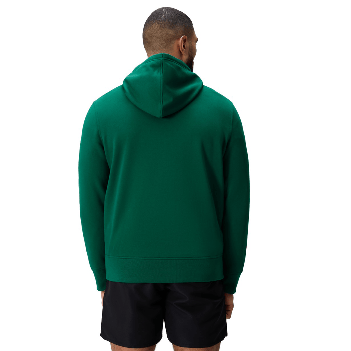 A person stands facing away, wearing a green Canterbury Uglies Logo Hoodie and black shorts against a plain white background.